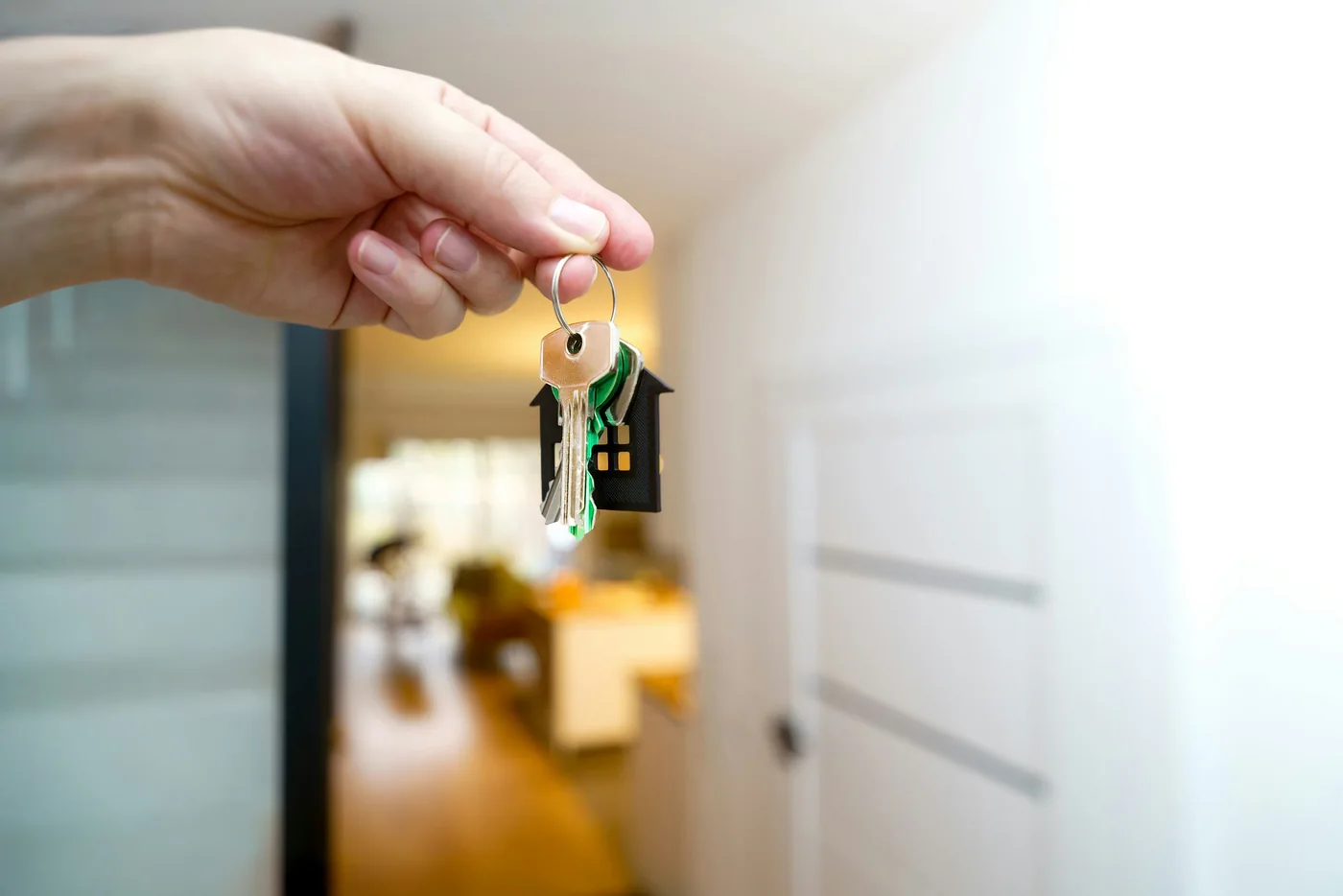 A hand holding house keys near a doorway